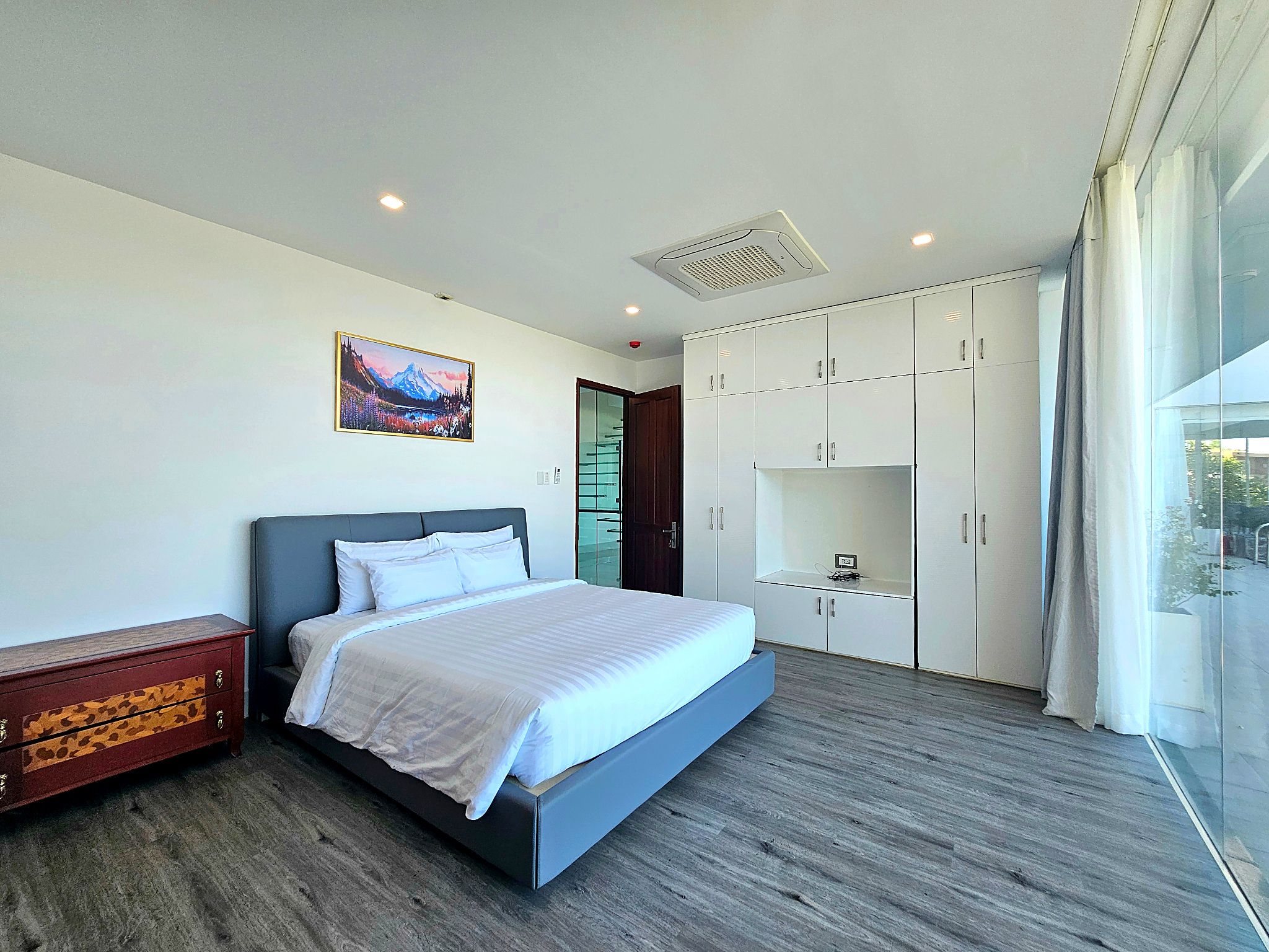 A modern bedroom with a bed, wardrobe, and a painting on the wall.