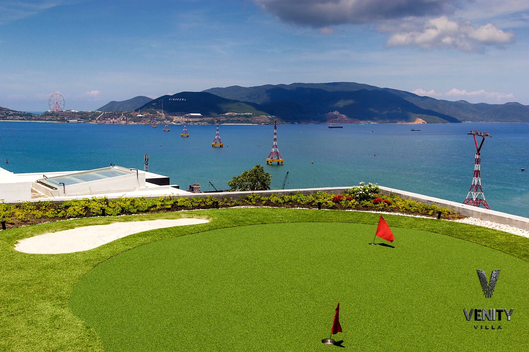 En golfbana med fri utsikt över havet och de avlägsna bergen.