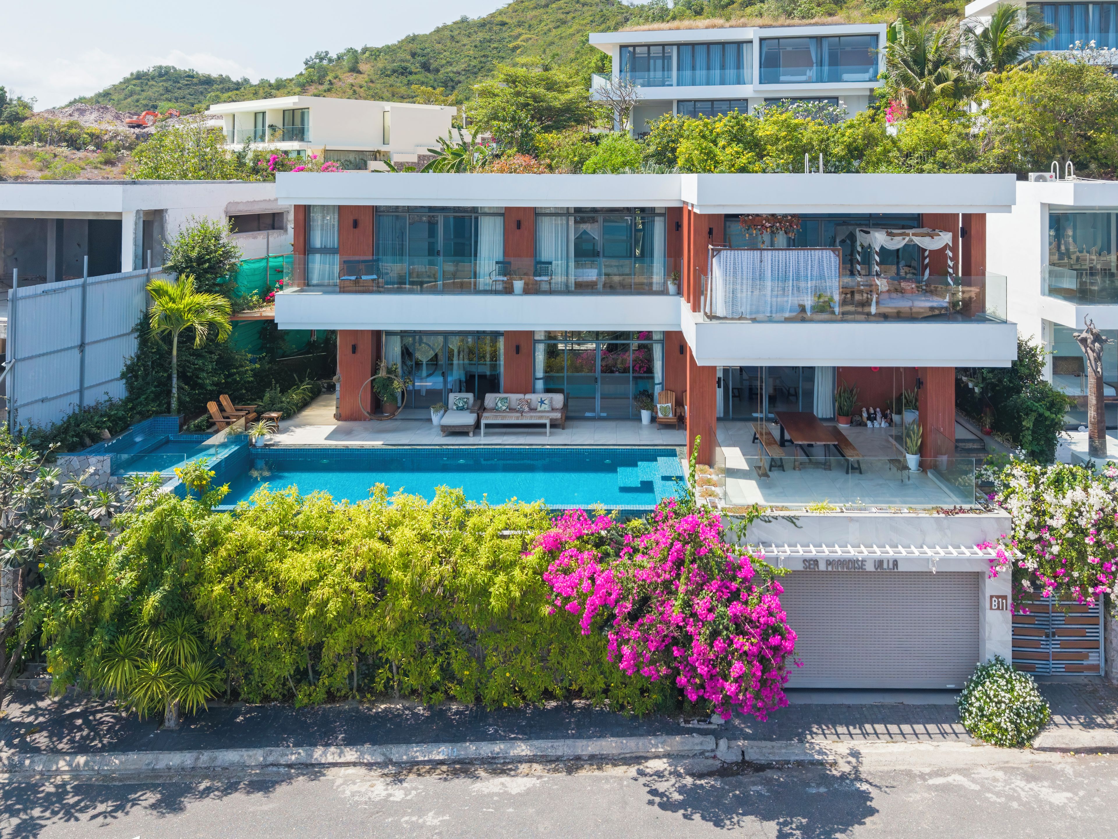 Eine moderne Villa mit Swimmingpool, Sitzgelegenheiten im Freien und üppiger Bepflanzung.