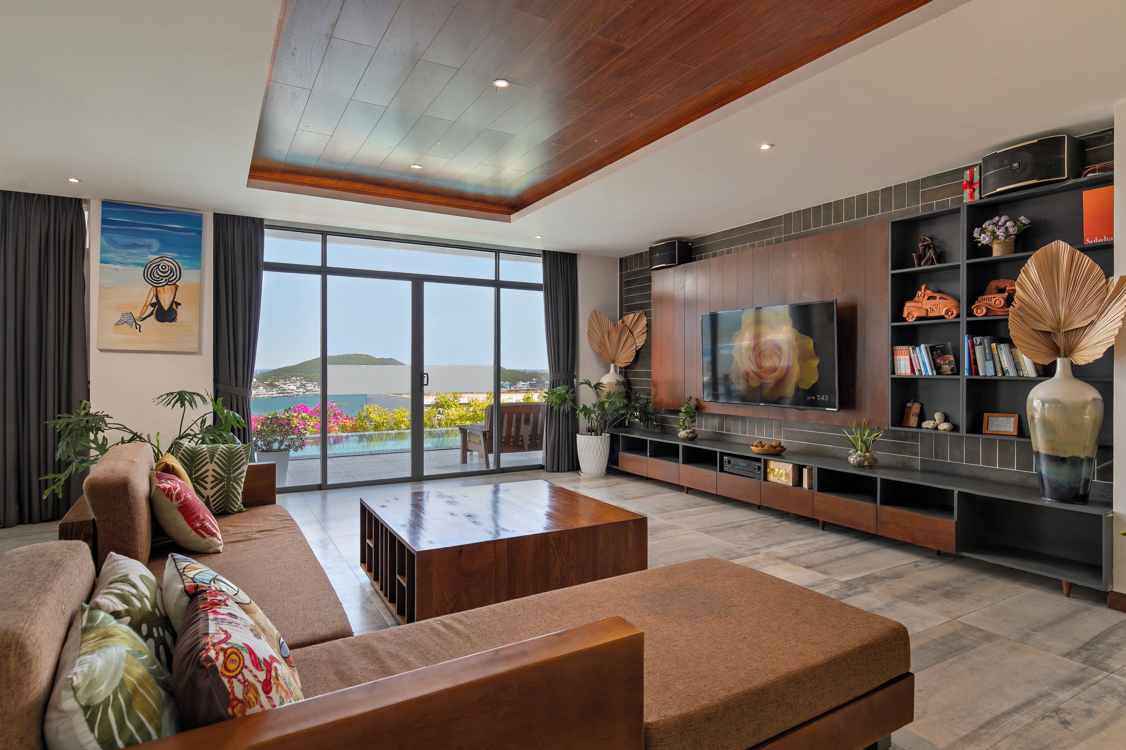 A modern living room with a large TV, comfortable seating, and a view of the outdoors.
