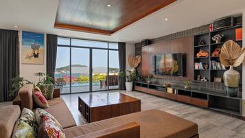 A modern living room with a large TV, comfortable seating, and a view of the outdoors.