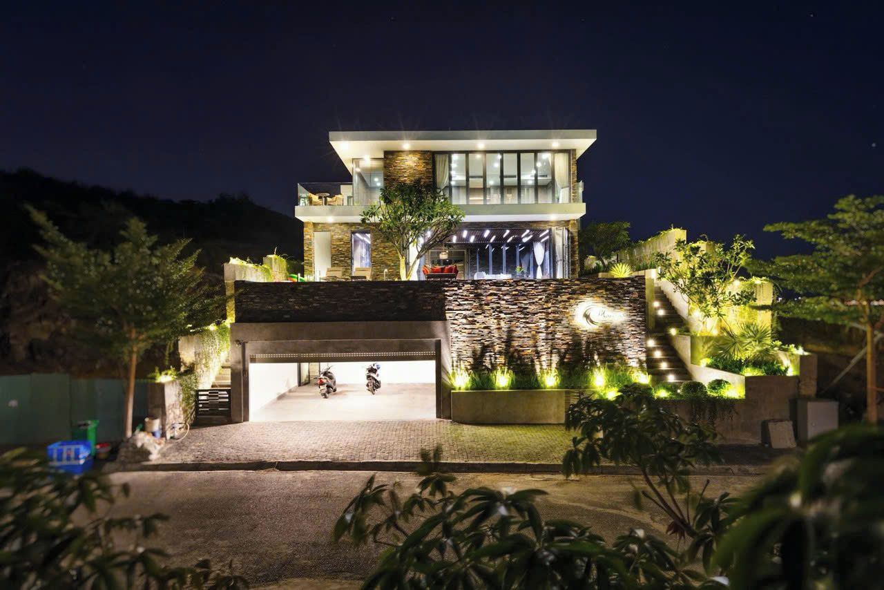 A modern two-story building with a stone facade, a covered entrance, and a landscaped garden area.