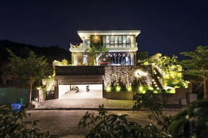 A modern two-story building with a stone facade, a covered entrance, and a landscaped garden area. - Koaniva Villa Ocean Beachfront Nha Trang (Nam Nha Trang)