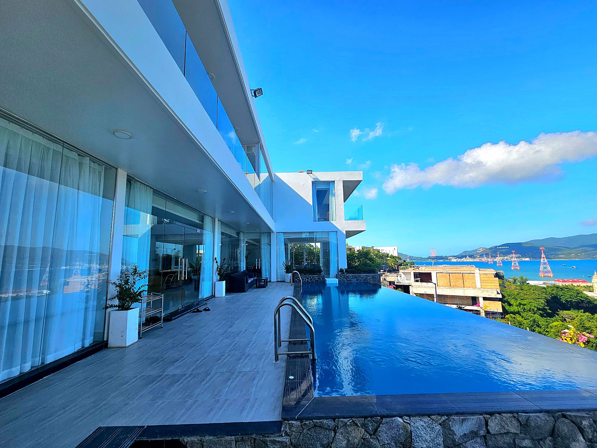 A modern building with a swimming pool, large windows, and a view of the sea.