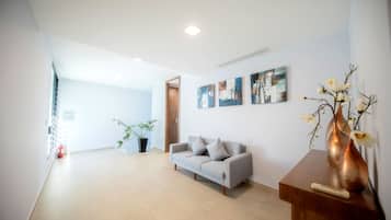 A modern living room with a grey sofa, a wooden coffee table, and a potted plant.