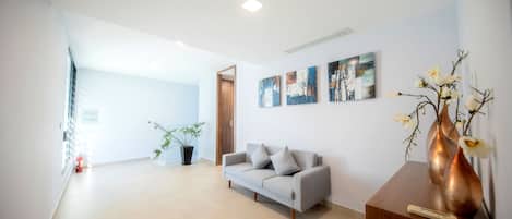 A modern living room with a grey sofa, a wooden coffee table, and a potted plant.
