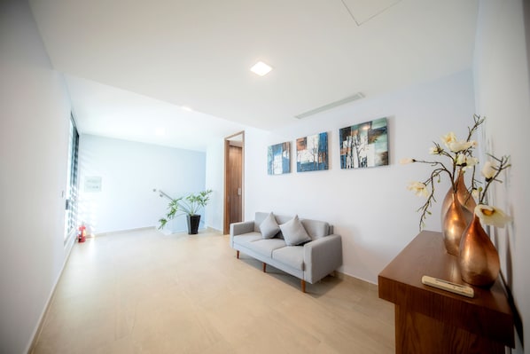 Una sala de estar moderna con un sofá gris, una mesa de centro de madera y una planta en maceta.