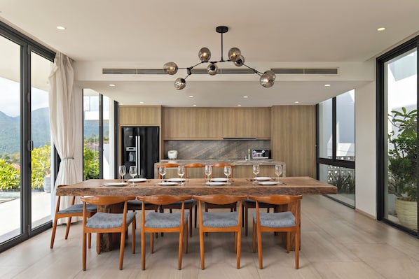 A modern dining area with a large wooden table, six chairs, and a contemporary chandelier.