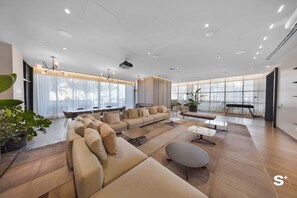 A spacious living room with a large sectional sofa, a coffee table, and a dining area with a table and chairs. - Skyline Views Condo | Pool | Gym | Near Kaseya (Miami)
