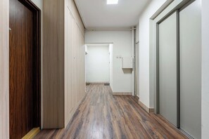 A hallway with wooden flooring, white walls, and a closed door on the left. - Warsaw Stay Near Shops (Warsaw)