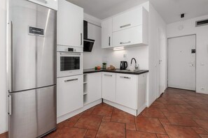 A modern kitchen with white cabinetry, a stainless steel refrigerator, an oven, and a Bosch microwave. - Warsaw Stay Near Shops (Warsaw)