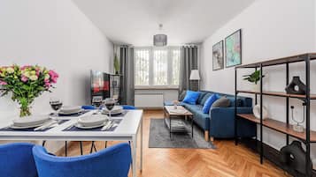 Een moderne woonkamer met een eethoek, een bank, een salontafel en een boekenkast.