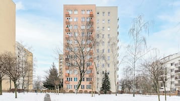 Een meerlaags woongebouw met een binnentuin en een met sneeuw bedekte grond.