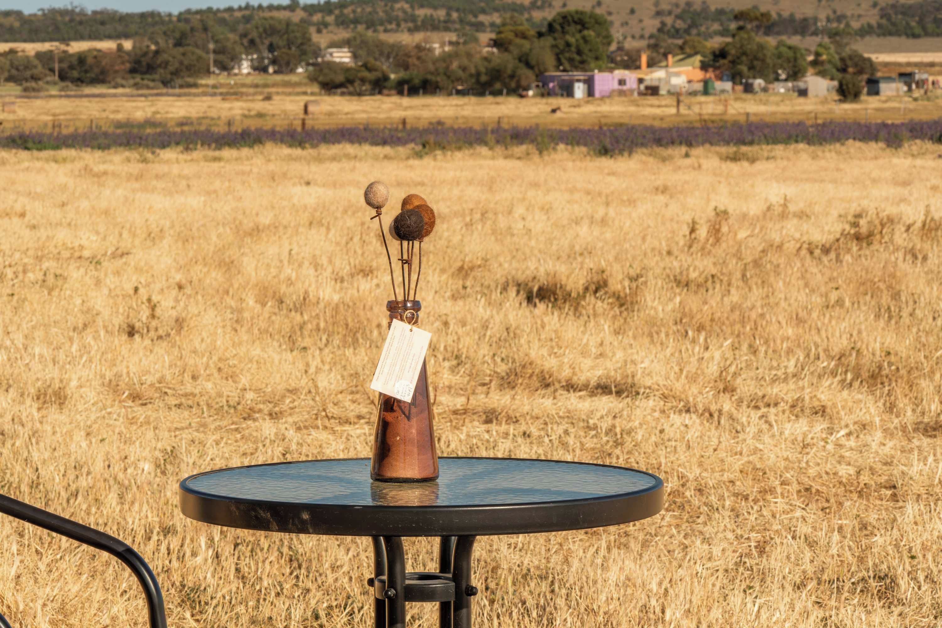 Una mesa redonda con base metálica, un objeto pequeño encima y una etiqueta adherida a la base.