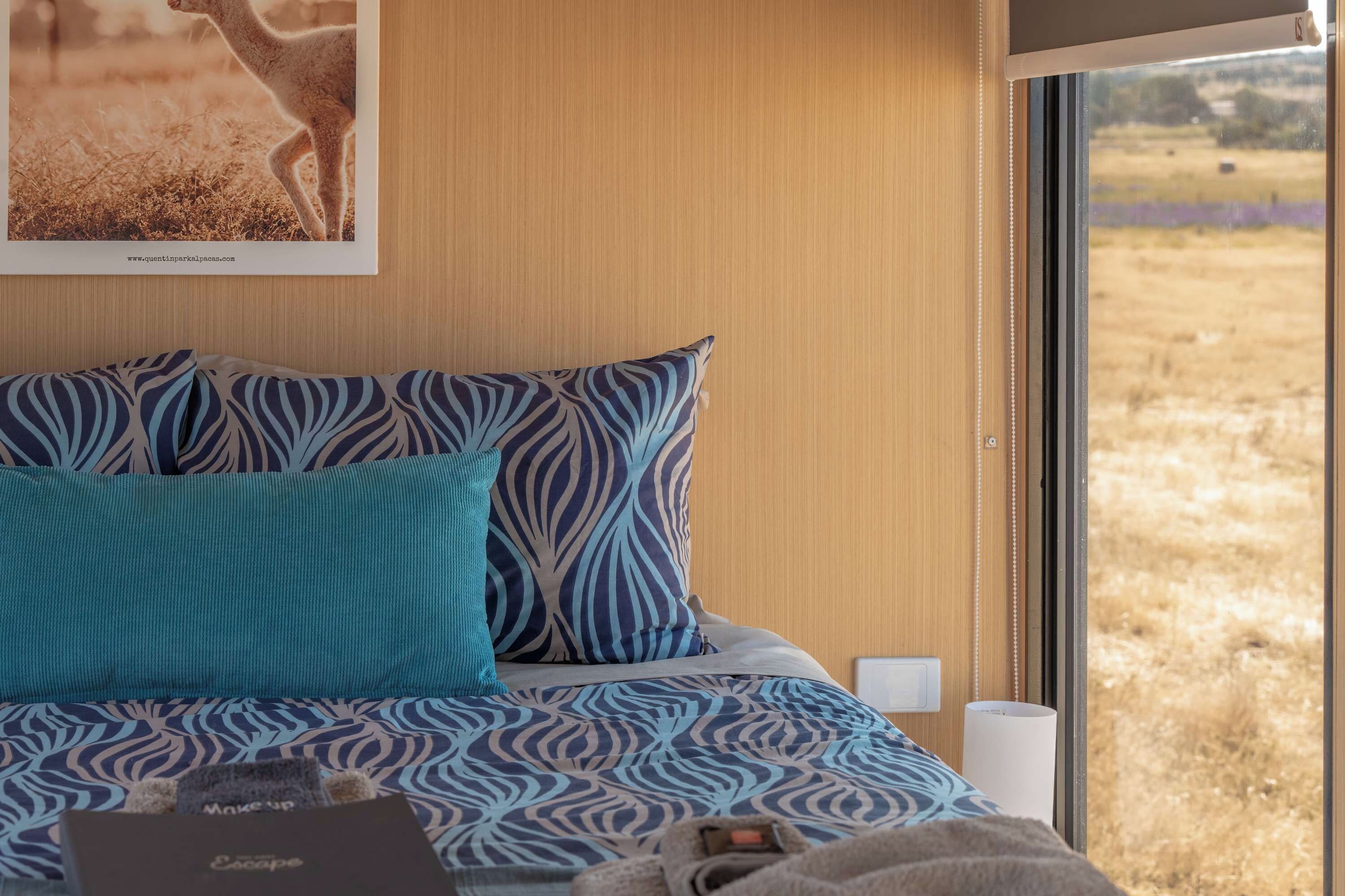 A bedroom with a bed, pillows, a window, and a poster on the wall.