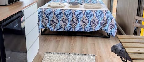 Quarto com cama, escrivaninha equipada com micro-ondas, geladeira e janela com vista, além de ar-condicionado.