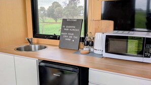 Una cocina compacta con un lavamanos, un lavavajillas Hisense, un microondas y una ventana con vistas a un paisaje verde.