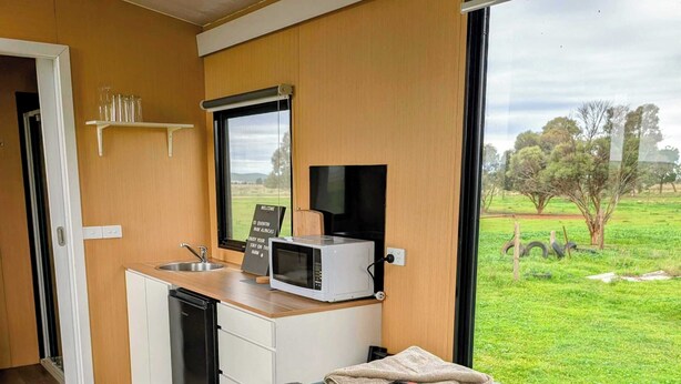 Un dormitorio con una cama, un escritorio con microondas, una computadora portátil y vistas a un paisaje verde.