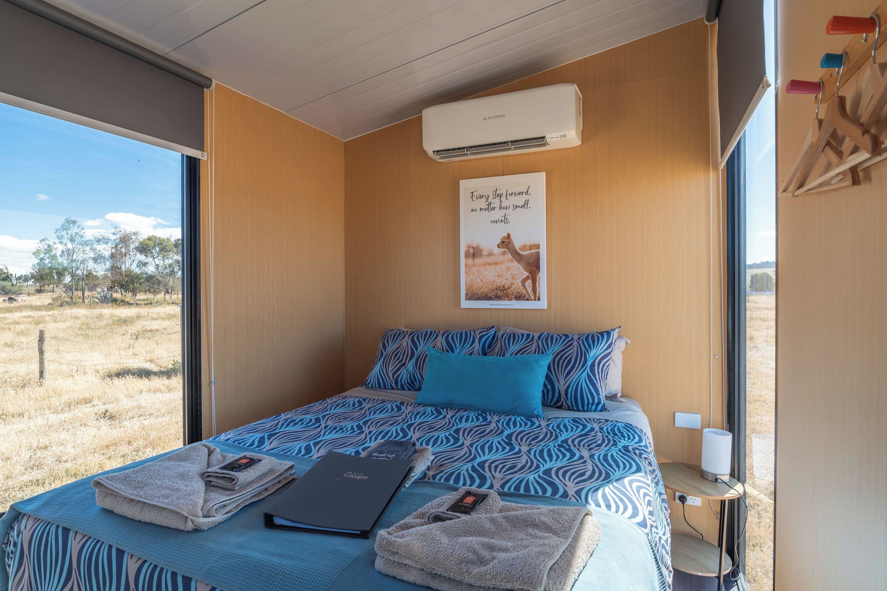 A room with a bed, a poster, an air conditioning unit, and a view of the outdoors.