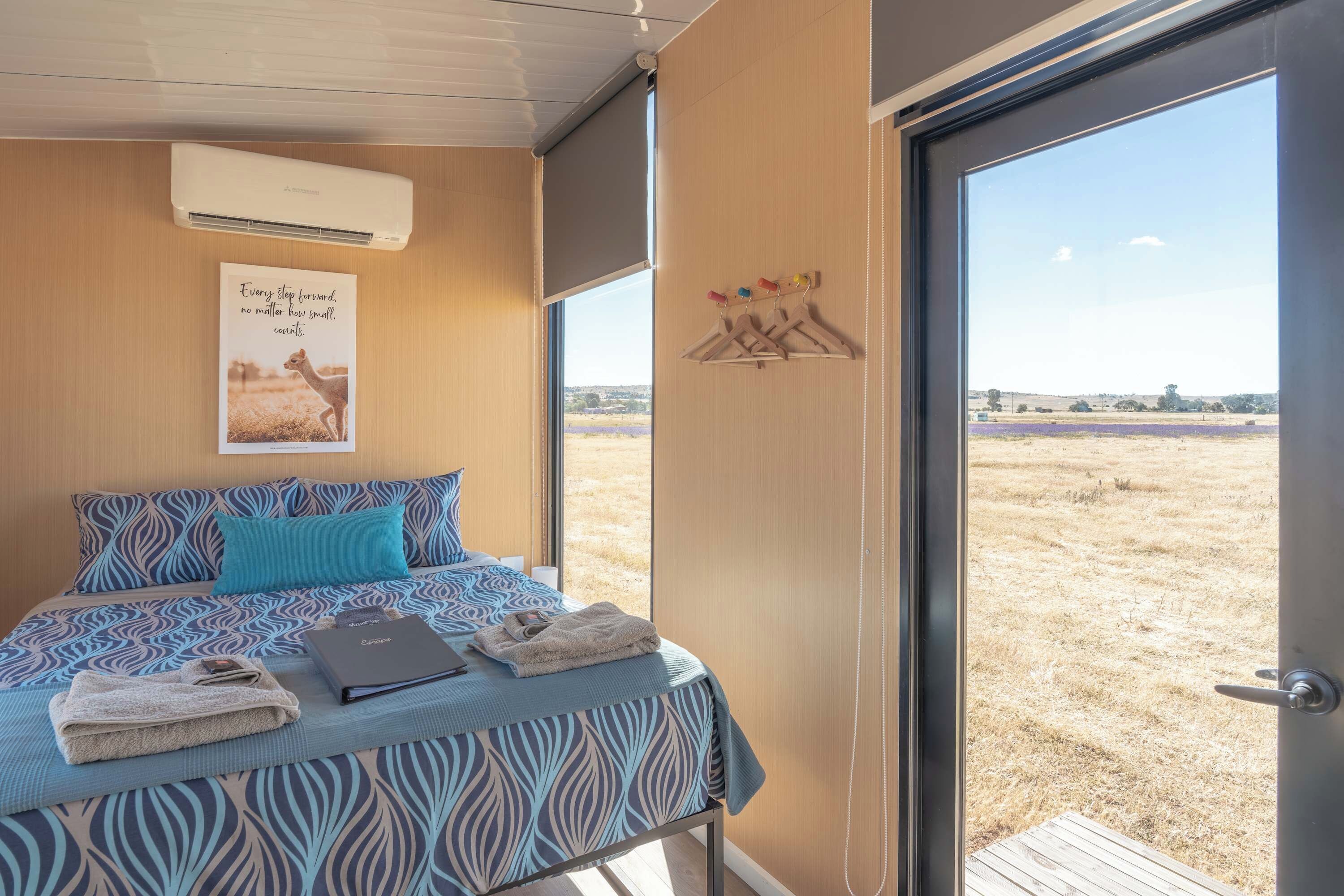 Un dormitorio con una cama, un cartel y vistas a un campo por una puerta.
