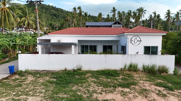 Una villa moderna con techo de tejas rojas, paredes exteriores blancas y un letrero que dice 'Ve Cocon Villa'.
