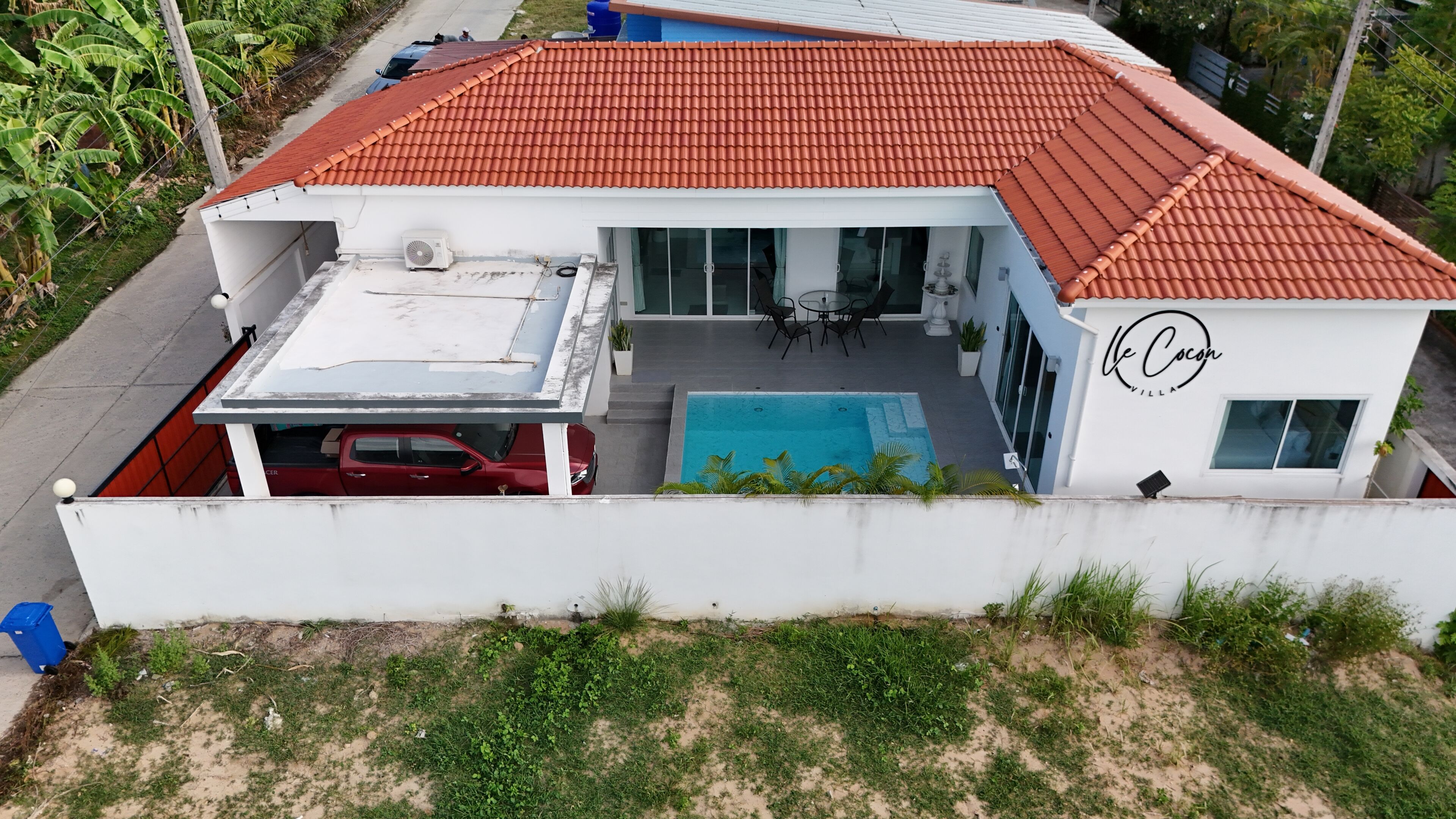 A modern house with a red tiled roof, a swimming pool, and a covered carport.