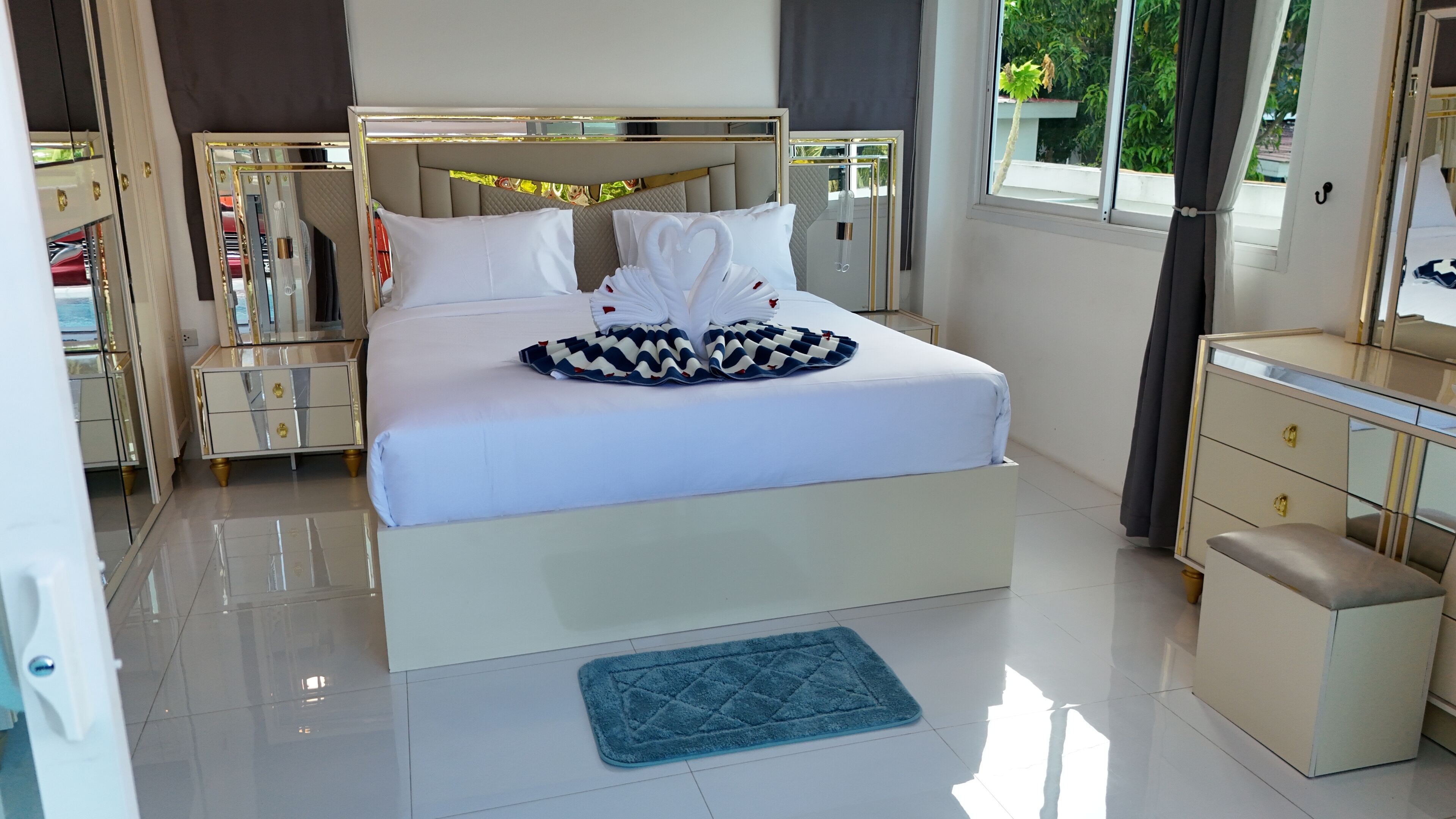 Habitación de hotel con una cama grande, una mesita de noche, un aparador y una ventana con cortinas.