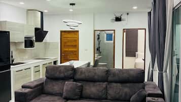 Una sala de estar moderna con un sofá modular, una mesa de centro y una cocina al fondo.