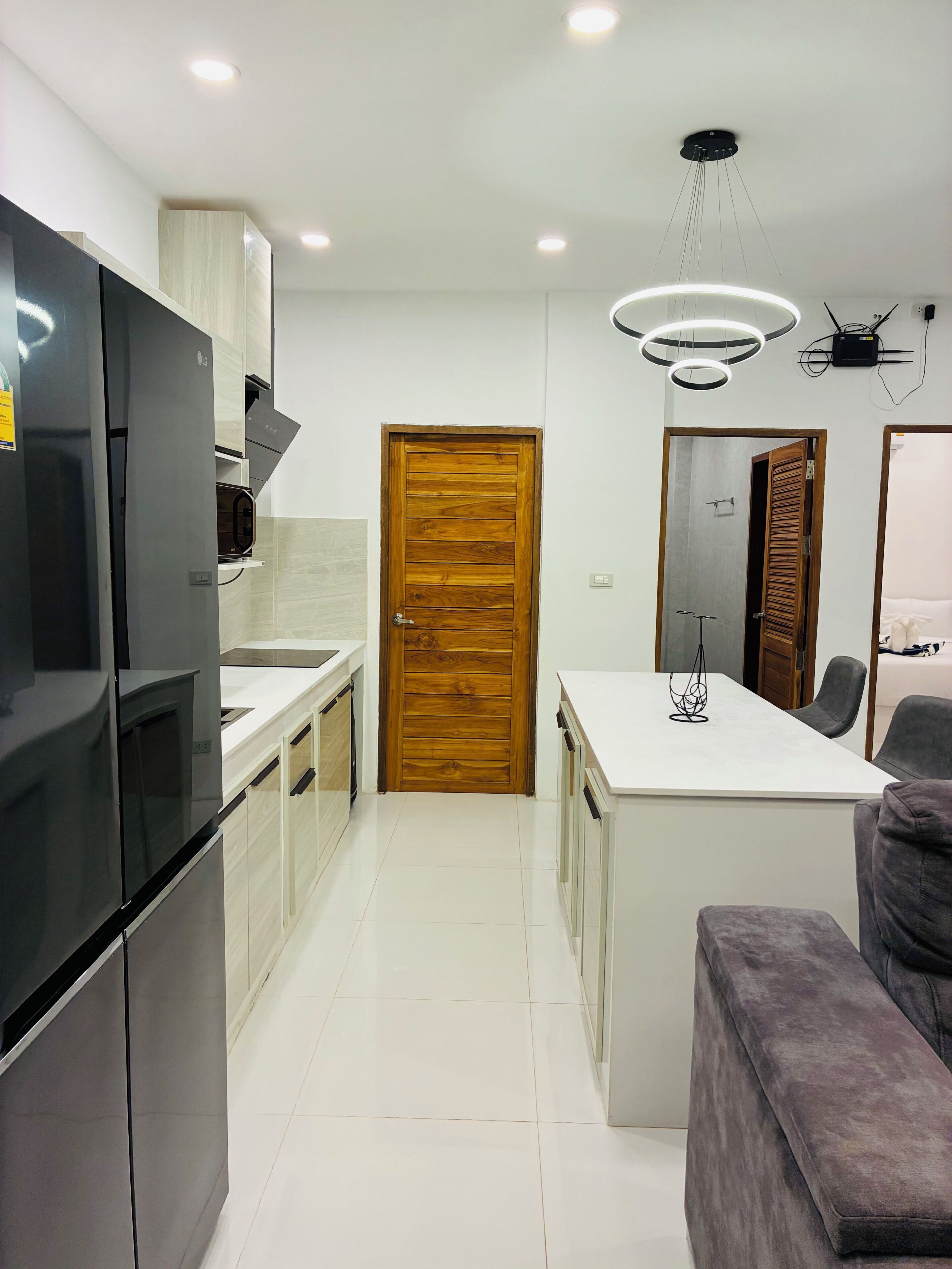 Una cocina moderna con una isla central, horno empotrado y puerta de madera.