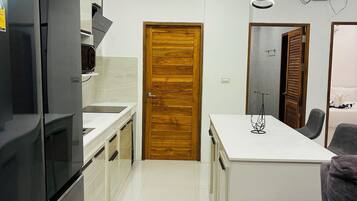 Una cocina moderna con una isla central, horno empotrado y puerta de madera.