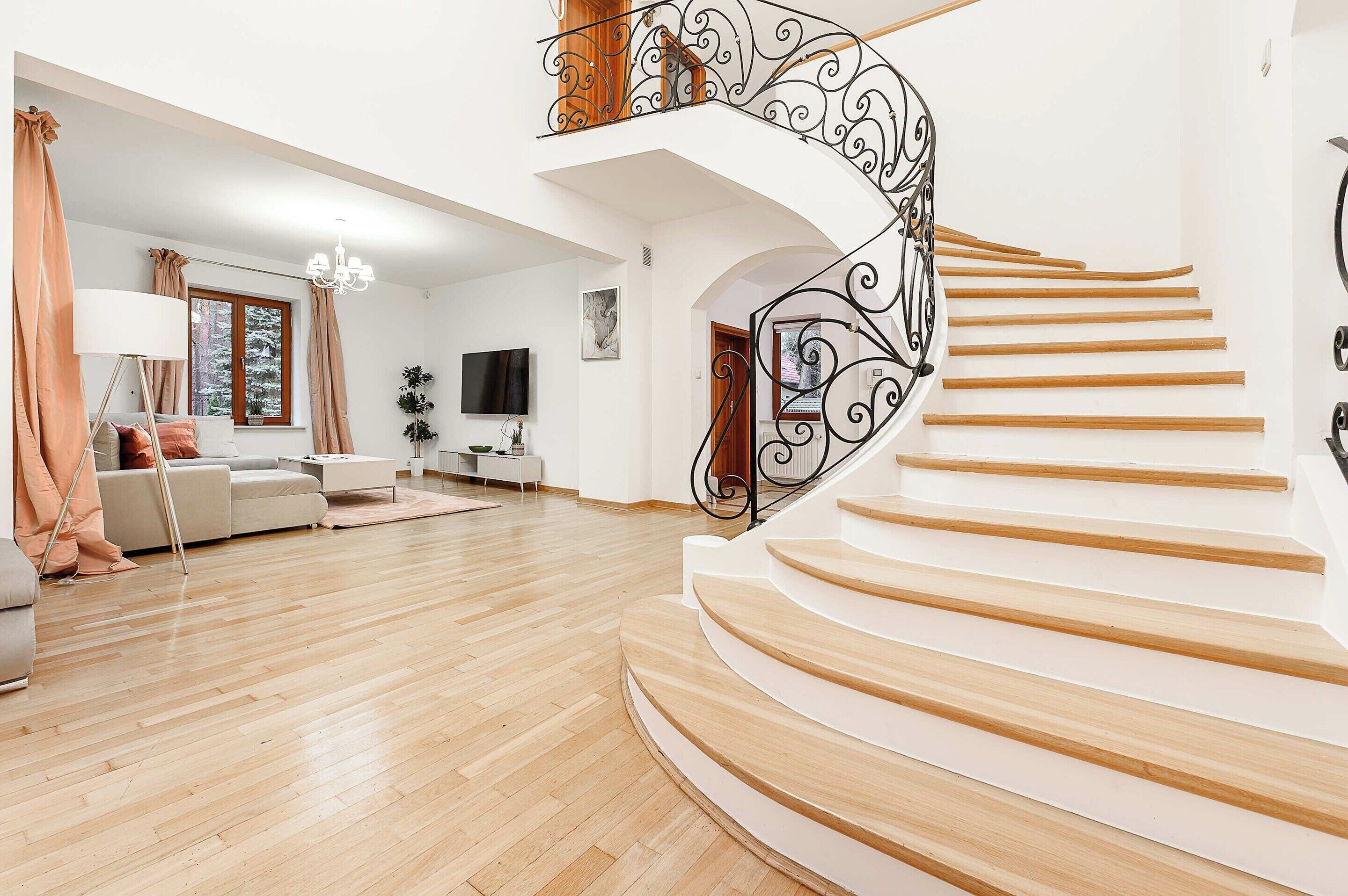 Un amplio salón con una escalera curva y un televisor.
