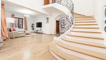 Un amplio salón con una escalera curva y un televisor.