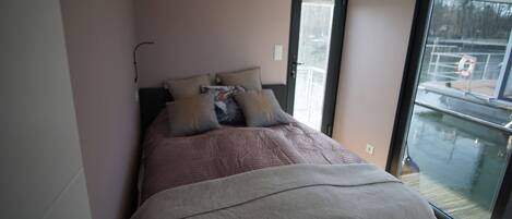 A bedroom with a bed, a window, and a door.