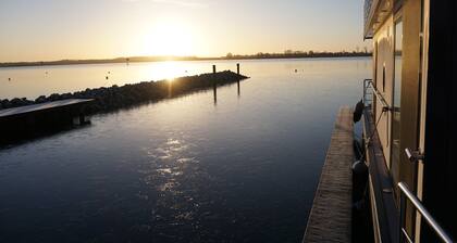 Modernes festliegendes Hausboot mit großzügiger Dachterrasse und Ruderboot