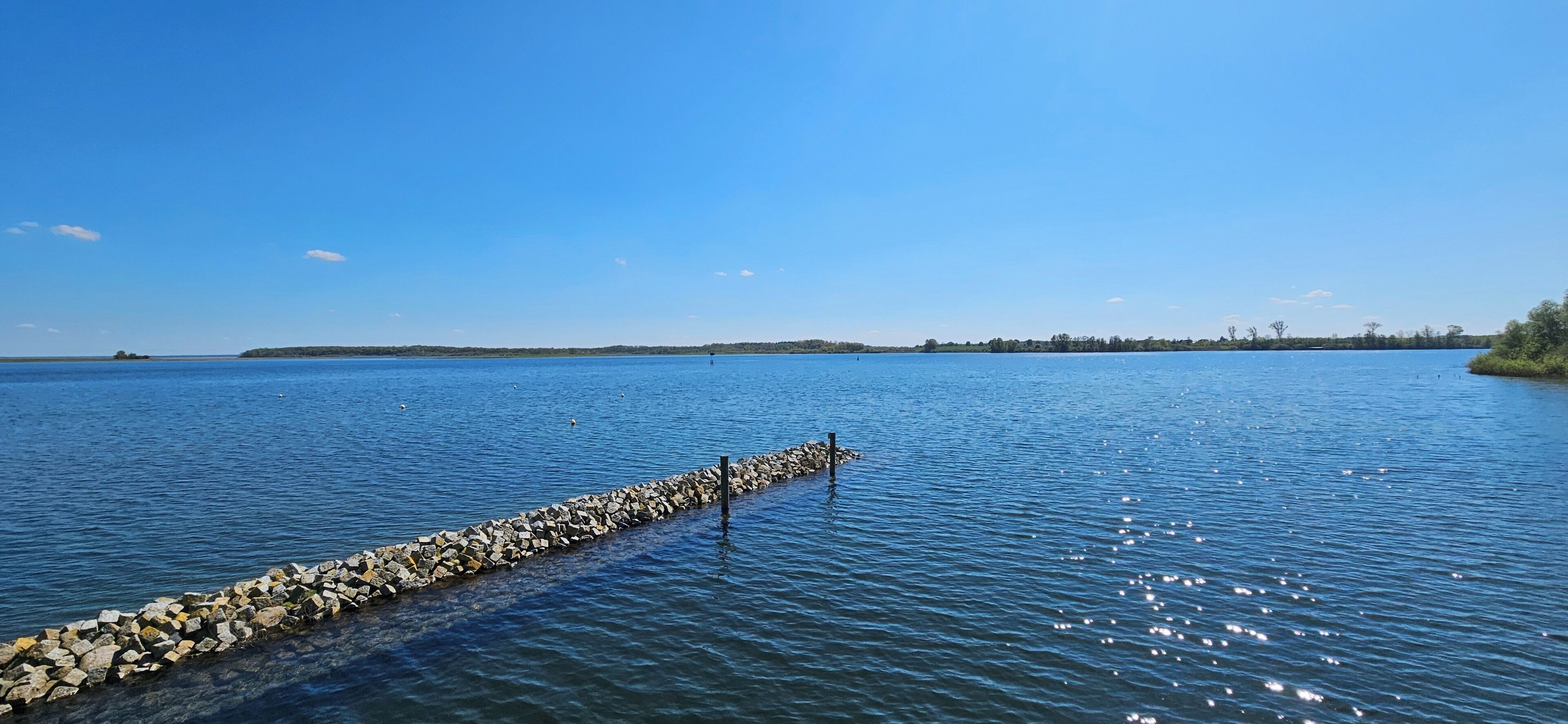 A calm lake with a rocky breakwater extending into the water.