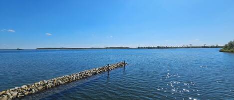 A calm lake with a rocky breakwater extending into the water.