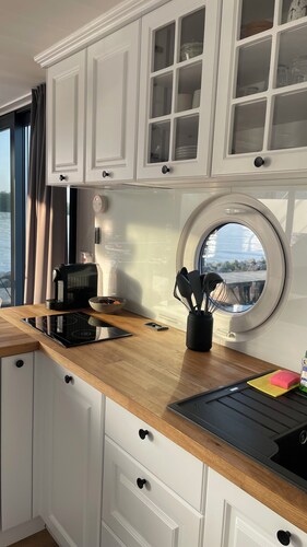Modernes festliegendes Hausboot mit großzügiger Dachterrasse und Ruderboot