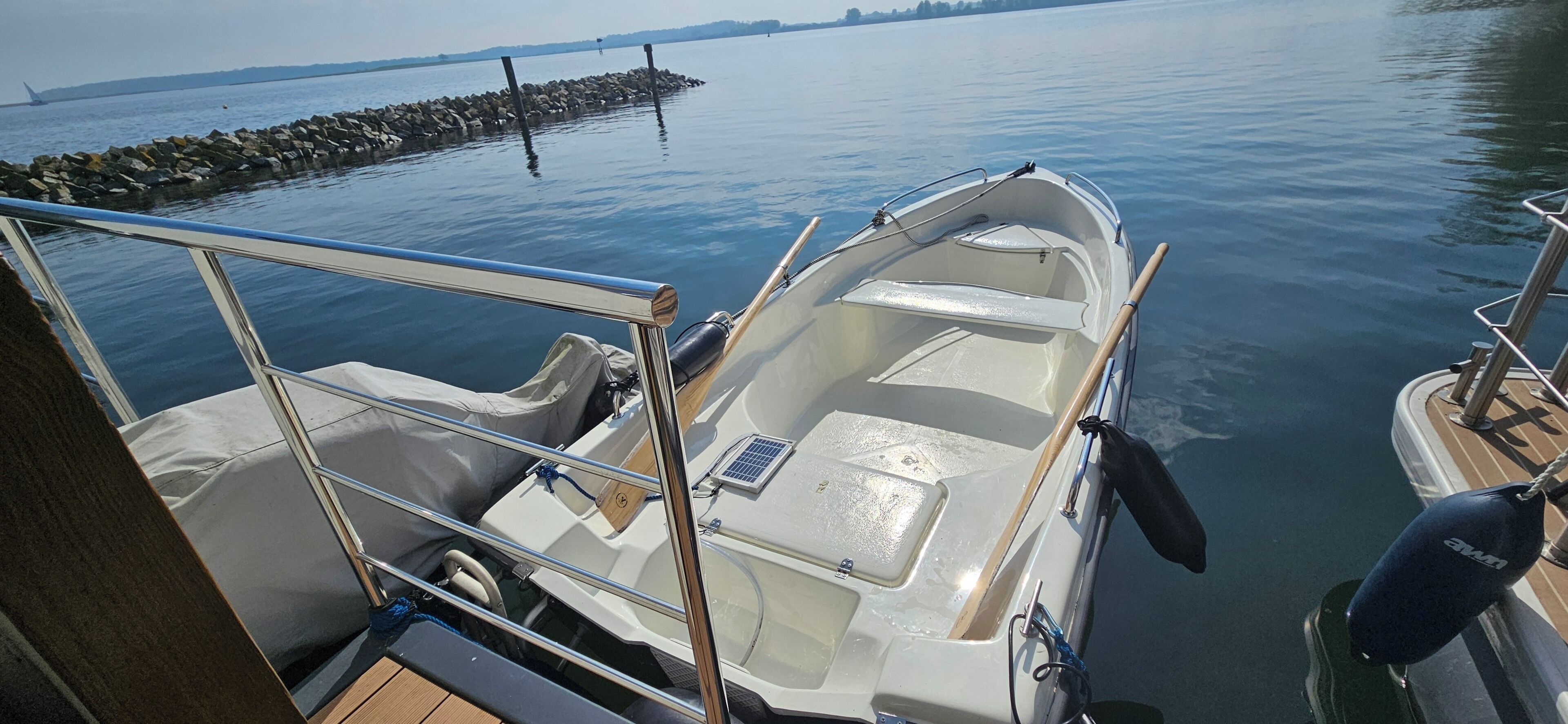 A boat docked at a pier with a view of the water and a distant landmass.