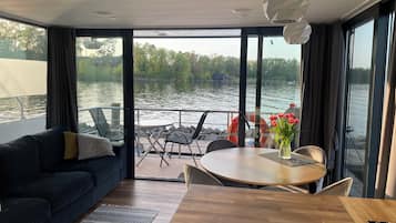 Une chambre moderne dotée d’une grande porte-fenêtre coulissante qui donne sur une terrasse offrant une vue sur un plan d’eau.