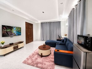 Una sala de estar moderna con un sofá, una mesa de centro, un televisor de pantalla plana, un microondas y un mueble de madera.