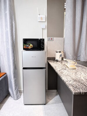 Una cocina compacta con un refrigerador Hisense, un microondas y una cafetera en la encimera.