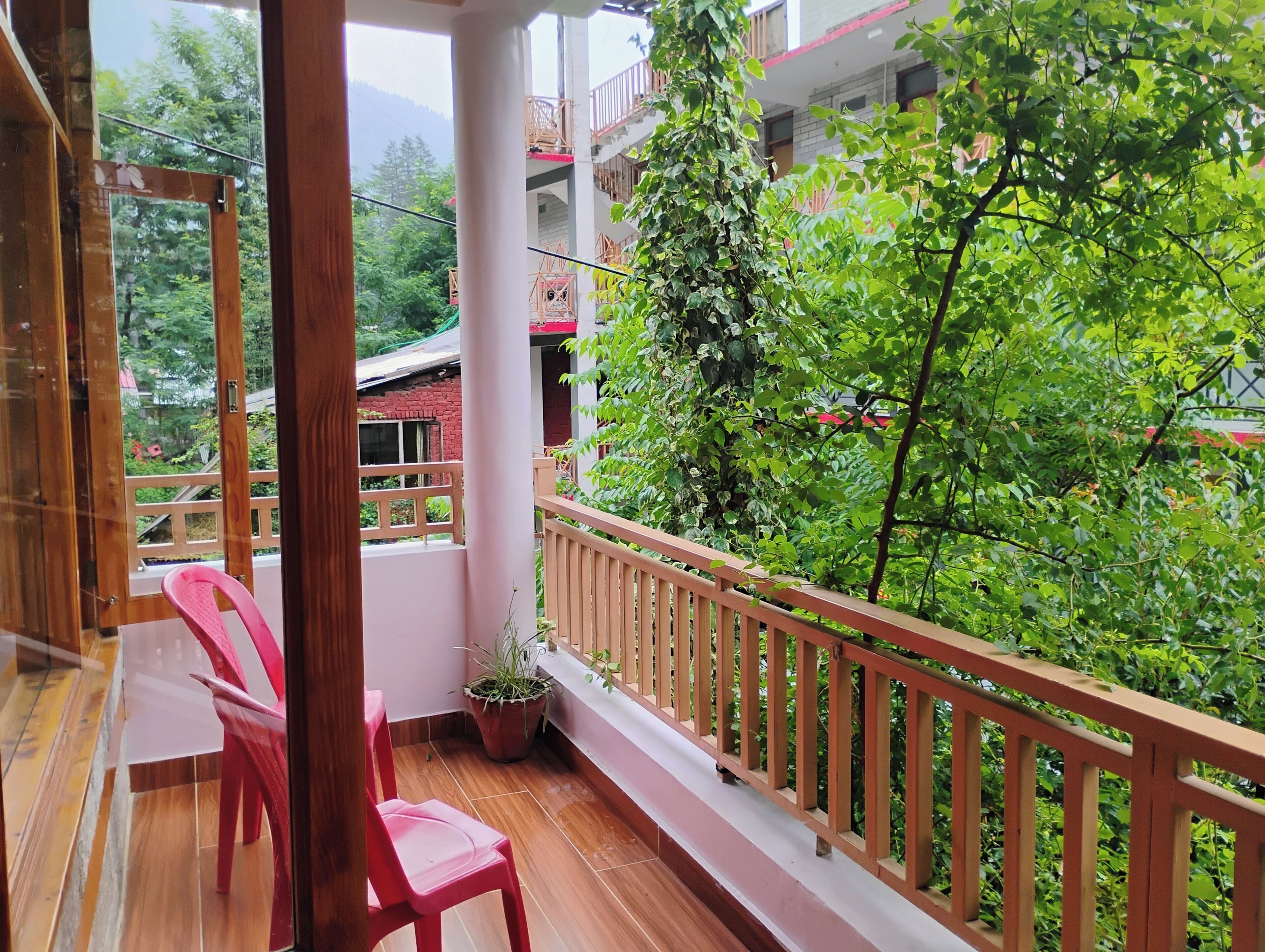 Ein Balkon mit Holzboden, einem Blumentopf und einem roten Stuhl.