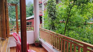 Ein Balkon mit Holzboden, einem Blumentopf und einem roten Stuhl.