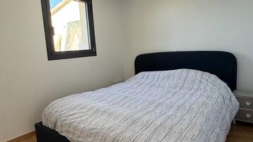 A bedroom with a single bed, a window, and a nightstand.