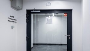 Una puerta con un panel de vidrio, un letrero de salida de incendios y flechas direccionales en la pared.