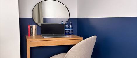 A corner desk with a laptop, a mirror, and two bottles of water.