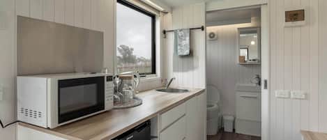 Cocina compacta con microondas, lavabo y una ventana pequeña.
