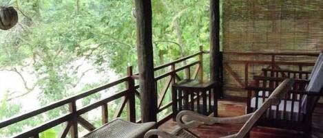 Un área de estar al aire libre cubierta con suelo de madera y barandillas de metal.