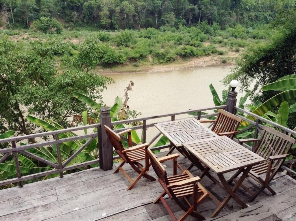 A wooden deck with a table and chairs overlooking a river.