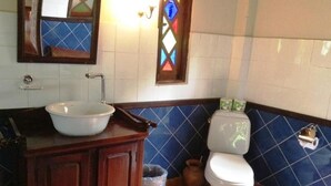 Un baño con lavamanos blanco, gabinete de madera, paredes con azulejos azules y un inodoro blanco.